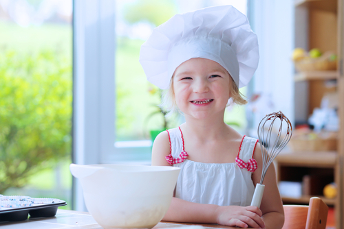 Young child baking with parents or au pair providing childcare