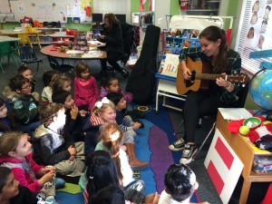 An au Pair plays music and sings to a classroom of young children.