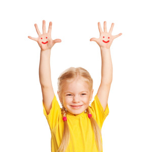 Happy child with hands raised and smiley faces on her palms.