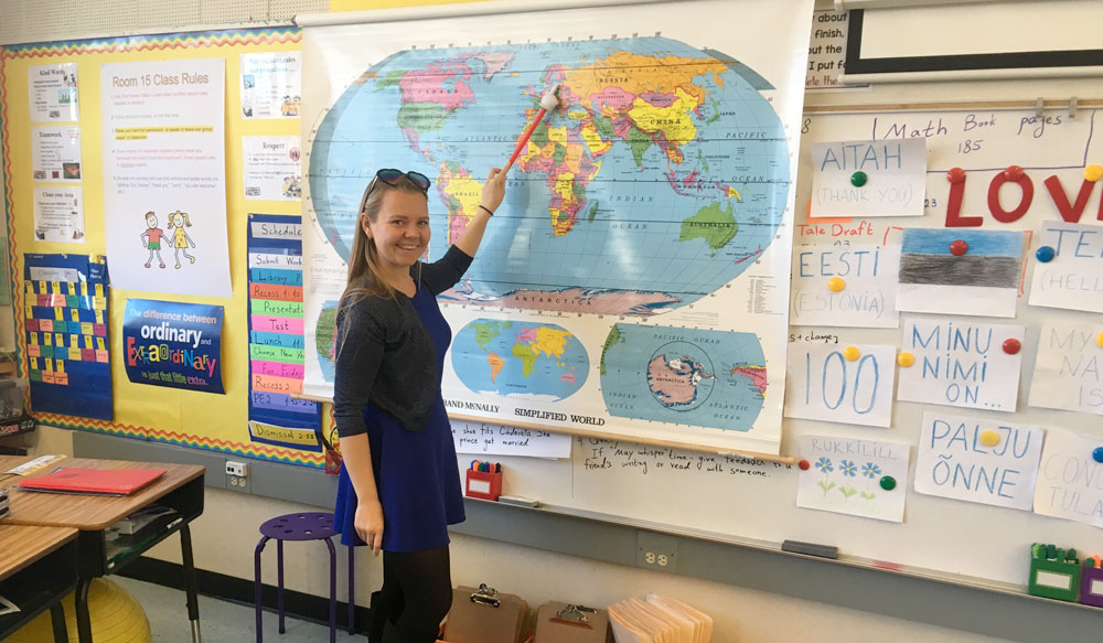 Au pair in an American school pointing at map