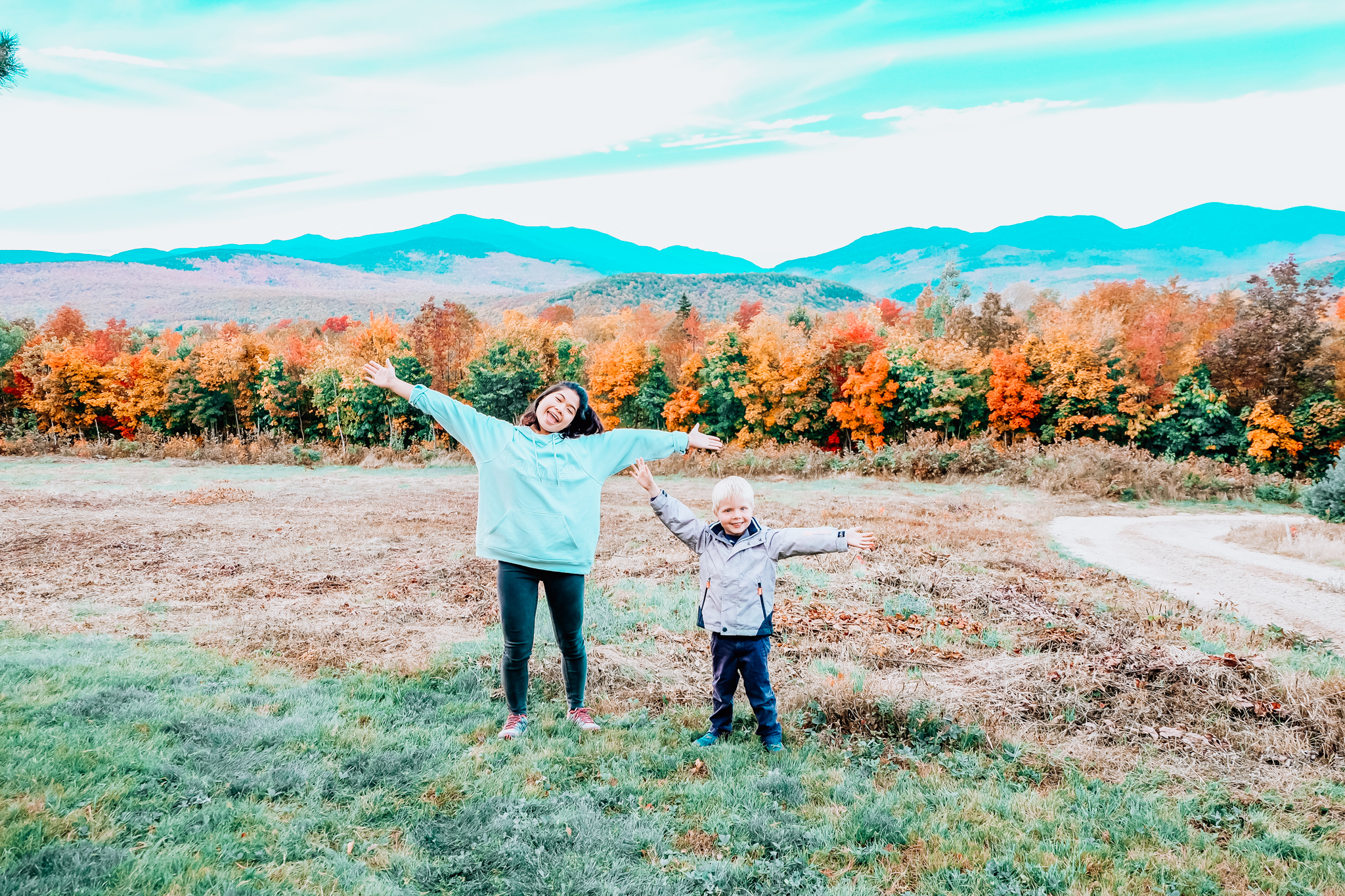 Au pair with host child in autumn foliage