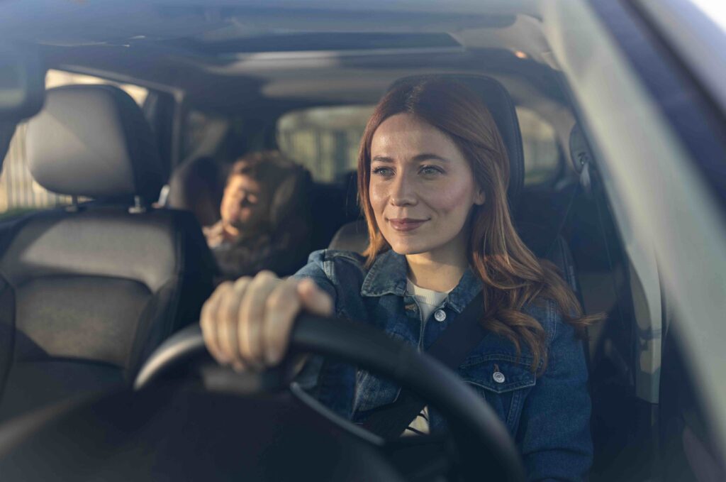 young woman driving child in car