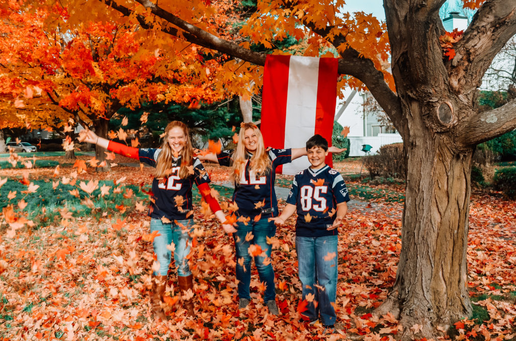 Austrian au pair with two teen host children playing in the leaves in front of flag of Austria