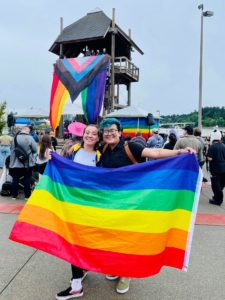 Au pair Taina with a friend holding Pride LGBTQIA+ flag