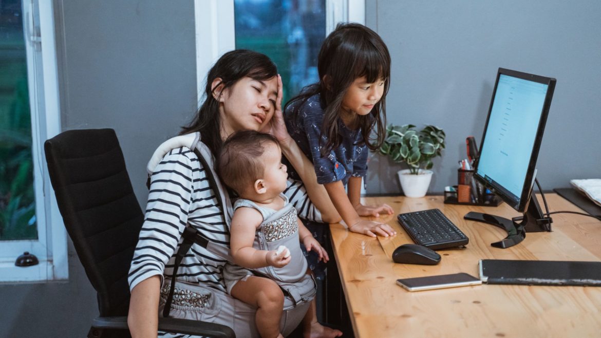 Stressed parent with two children sitting at computer desk