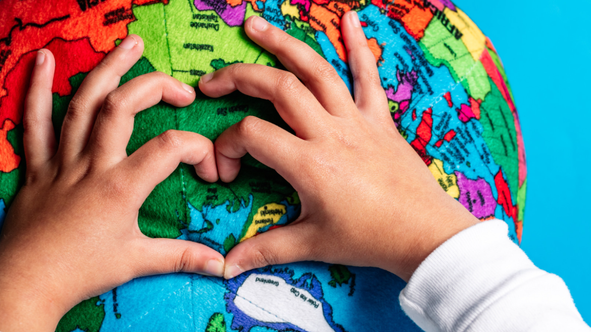 Child's hands in the shape of a heart on a globe