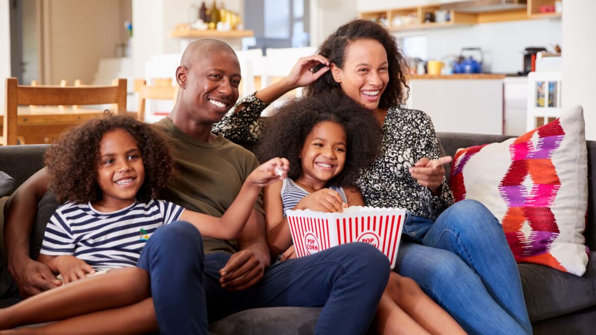 Family watching a movie with children on the couch with popcorn