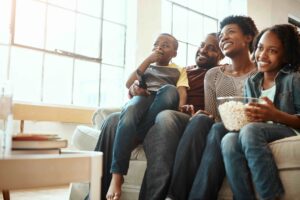 Family watching a movie with children on the couch with popcorn