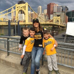 au pair with host children at a baseball game during spring season