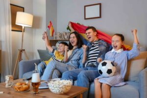 family watching soccer game at home holding flag of spain