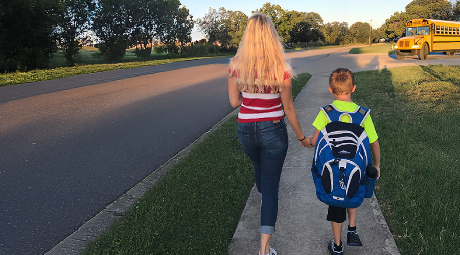 Au pair and host child walking to school bus